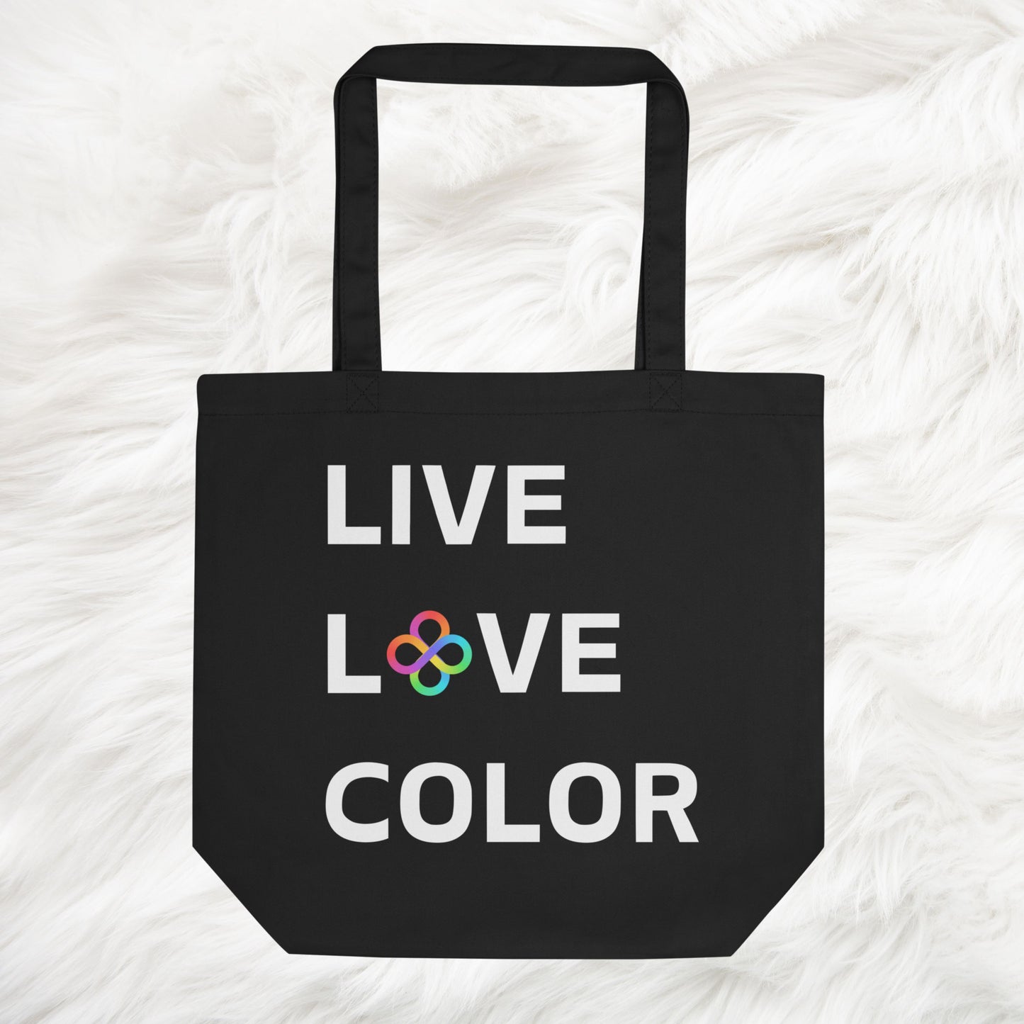 Black canvas tote bag with white bold print that says LIVE LOVE COLOR. The letter O in the word LOVE has been replaced with rainbow infinity symbols.