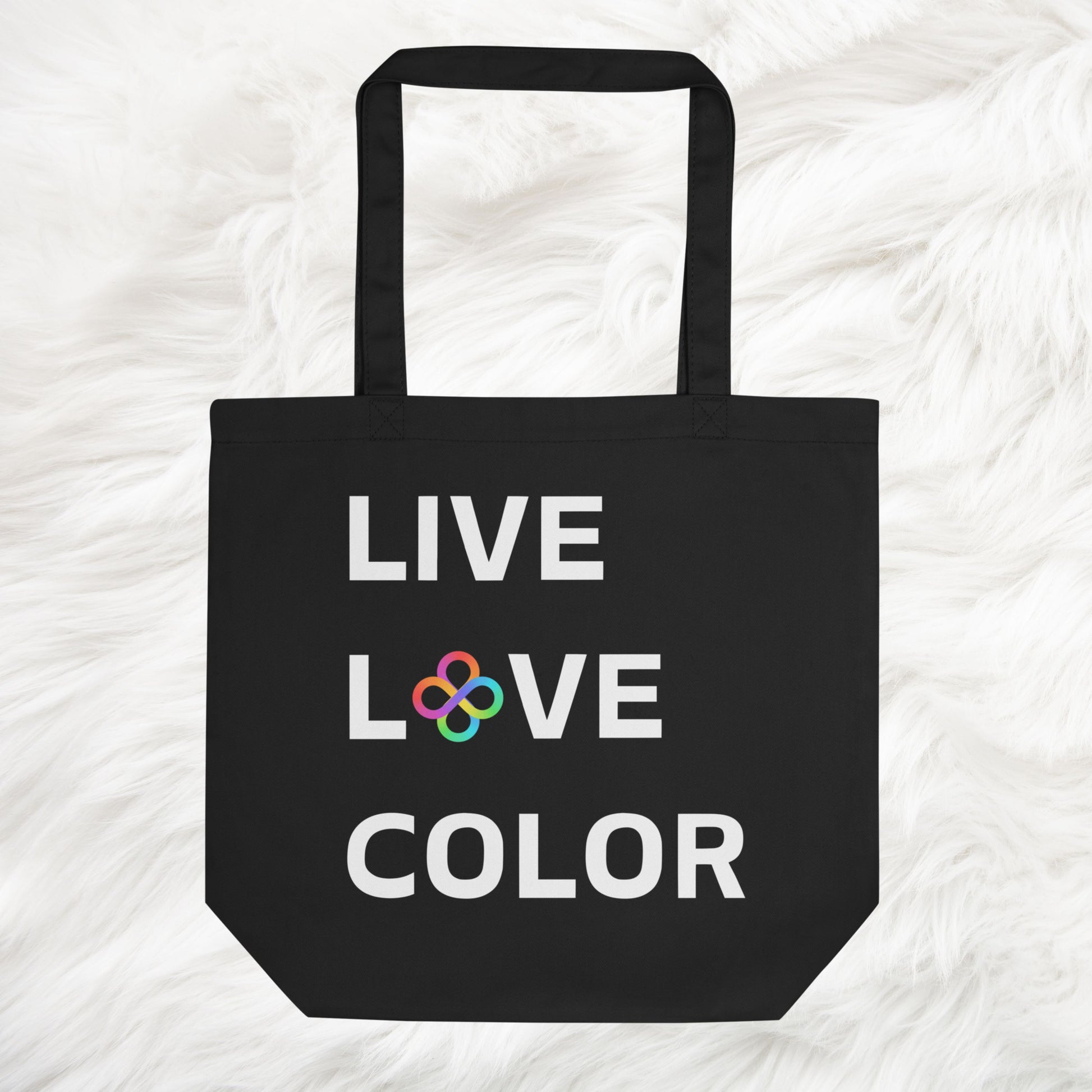 Black canvas tote bag with white bold print that says LIVE LOVE COLOR. The letter O in the word LOVE has been replaced with rainbow infinity symbols.