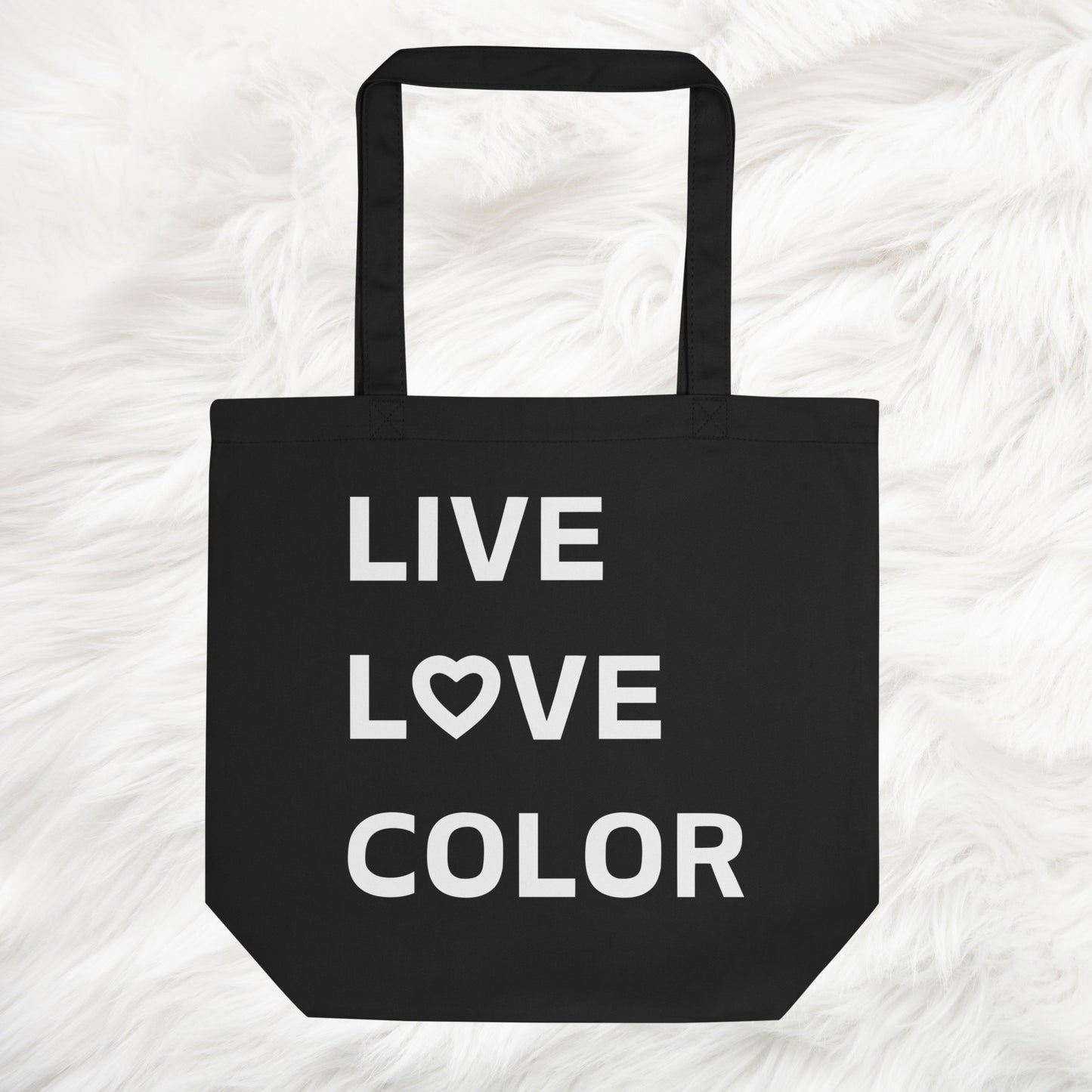 Black canvas tote bag with white bold print that says LIVE LOVE COLOR. The letter O in the word LOVE has been replaced with a heart symbol.