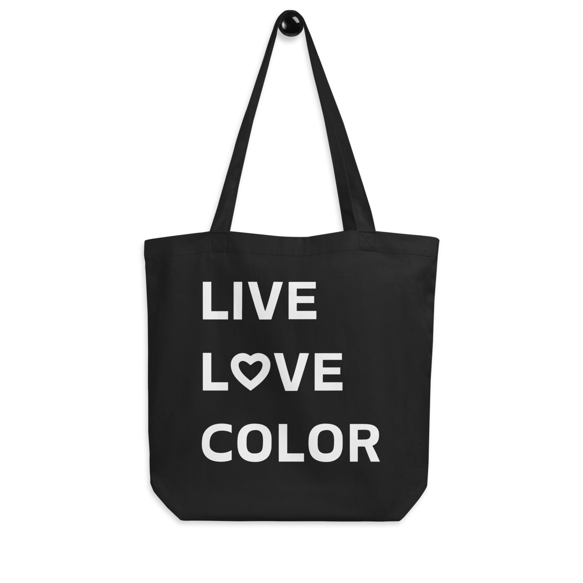 Black canvas tote bag with white bold print that says LIVE LOVE COLOR. The letter O in the word LOVE has been replaced with a heart symbol.