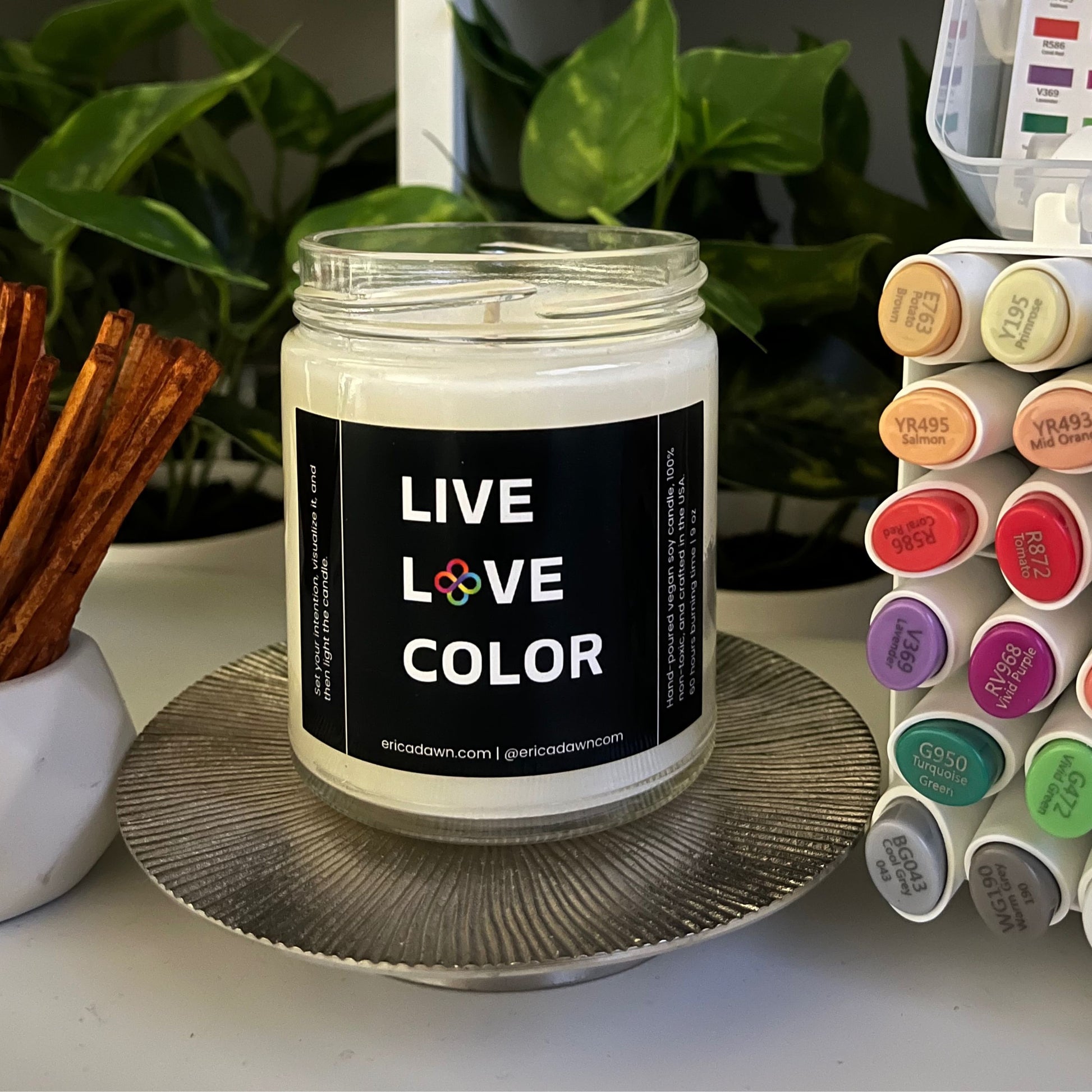 Hand-poured vegan soy wax candle. Soy wax inside a glass jar, a single cotton wick, with an outside label that says LIVE LOVE COLOR, with a screw top lid. The letter O in the word LOVE has been replaced with two rainbow infinity symbols.